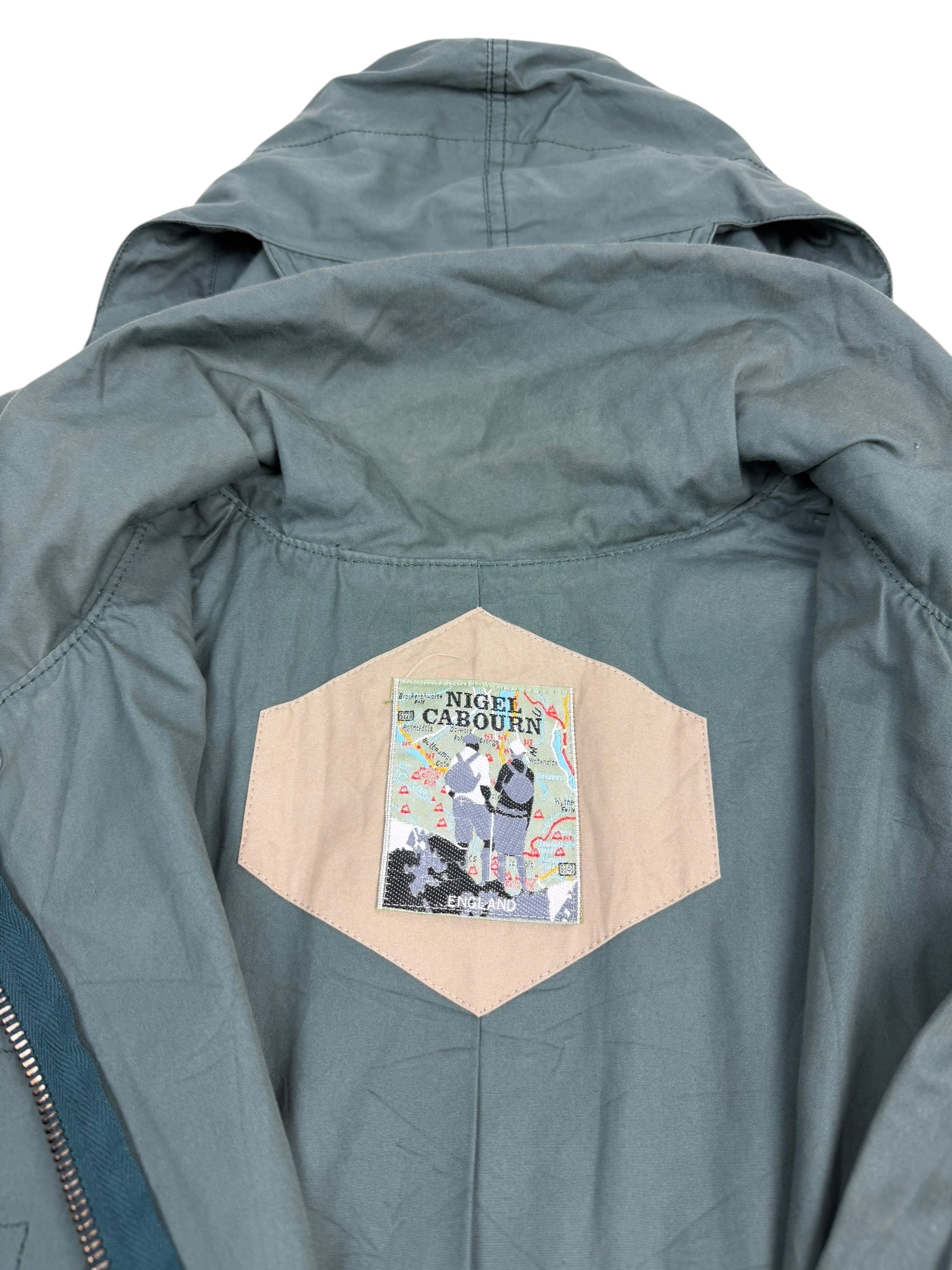 Green jacket with a patch on the back featuring 'Nigel Cabourn' branding.